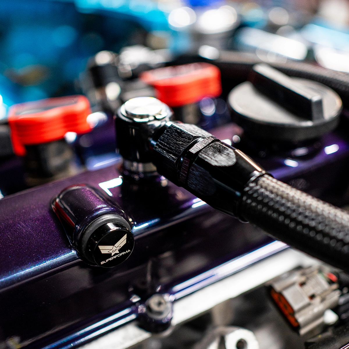 Detailed view of a AN10 custom braided hose and banjo fitting on a modified car engine with Superforma components