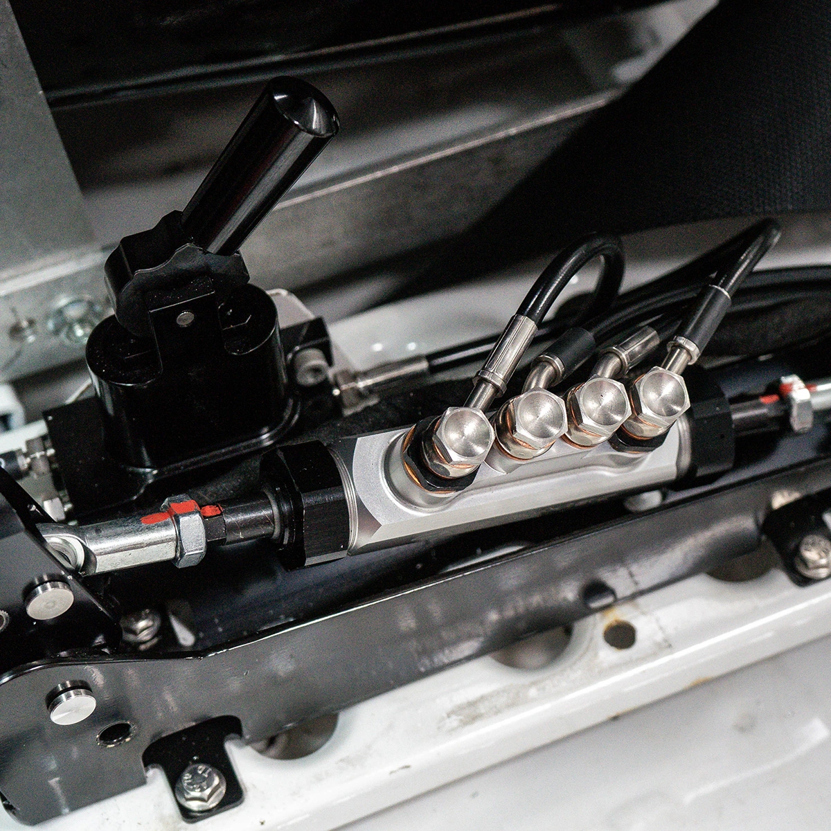 Close-up of hydraulic bias valve assembly with stainless steel braided brake lines in a race car interior