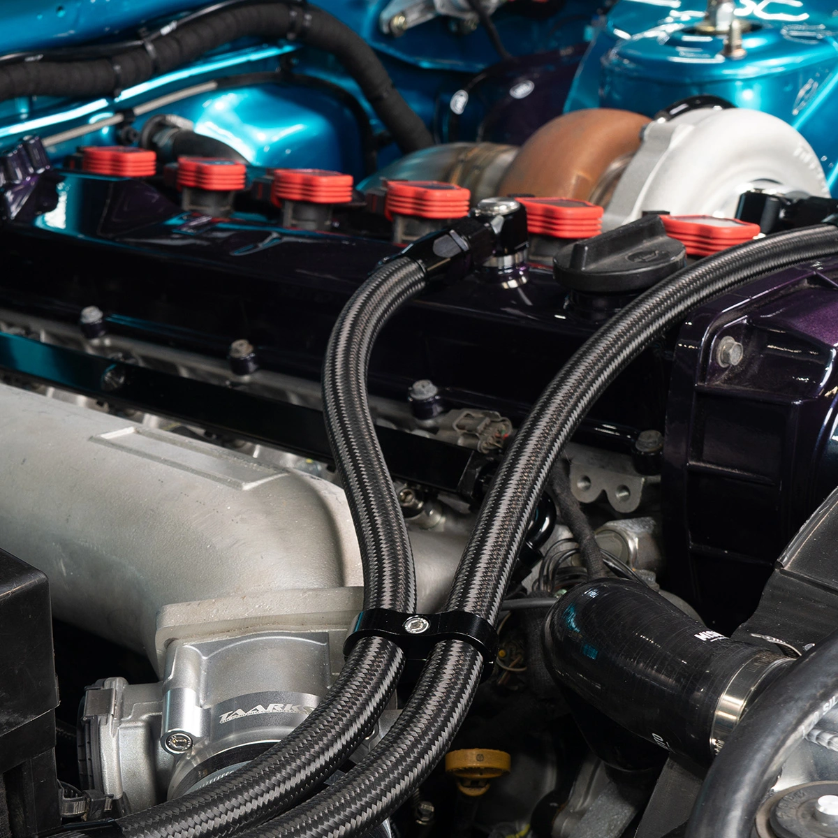 Twin custom braided hoses with AN fittings installed on a high-performance turbocharged engine with aftermarket components